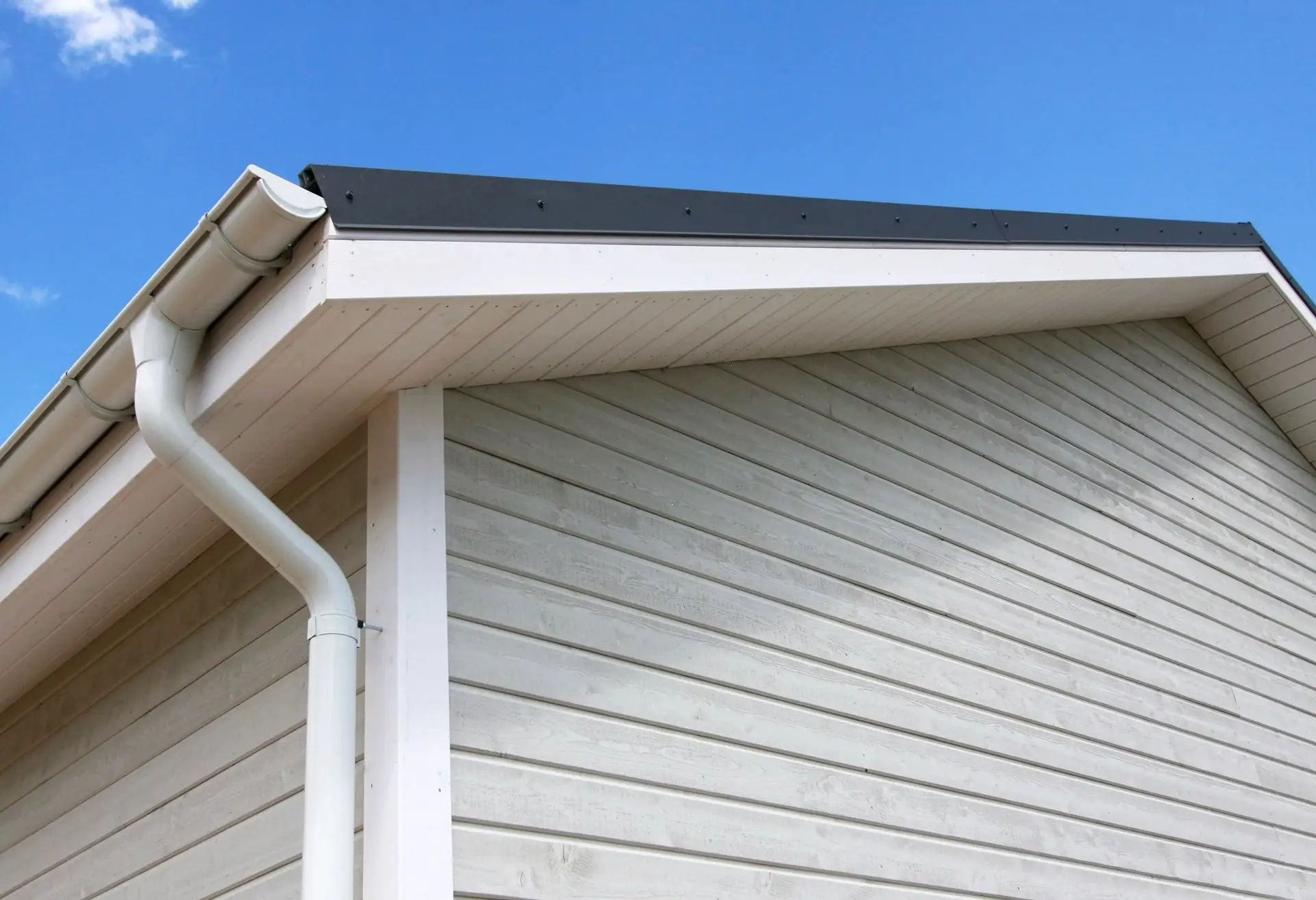 White seamless gutter and downspout on new siding
